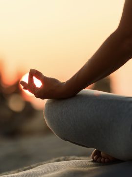 Close-up of woman practicing Yoga at sunset.