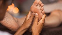 Foot reflexology massage Closeup of masseuse doing foot reflexology to woman at spa. Therapist hands doing foot massage at wellness center. Woman receiving a feet massage at health spa.