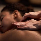 Closeup image of masseuse massaging neck of female client